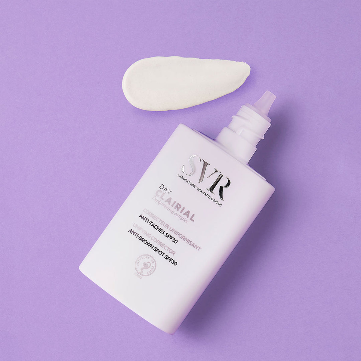 Flacon blanc SVR Clairial Day avec une noisette de crème sur fond violet, correcteur anti-taches SPF30.