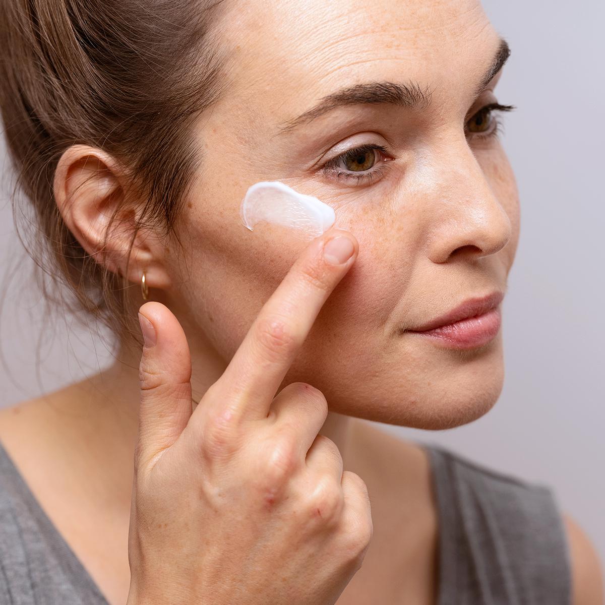 Femme appliquant la crème onctueuse PALPEBRAL sur le contour de ses yeux sensibles pour apaiser les irritations.