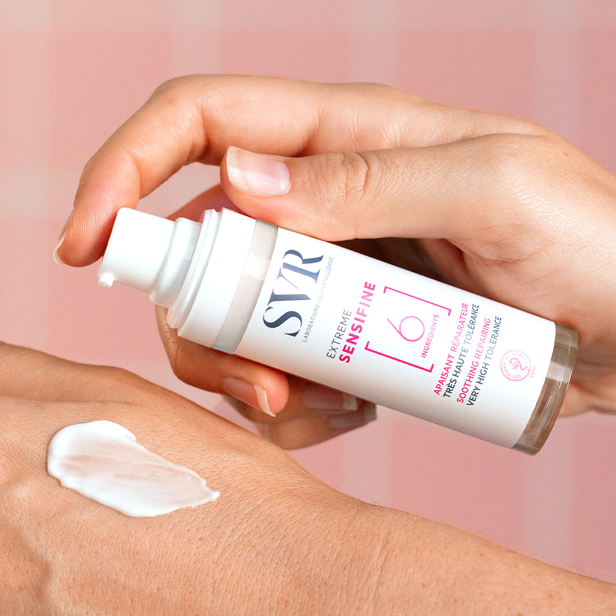 SVR Sensifine Extrême soothing repair cream in a white pump bottle with a dollop of white lotion on a hand.