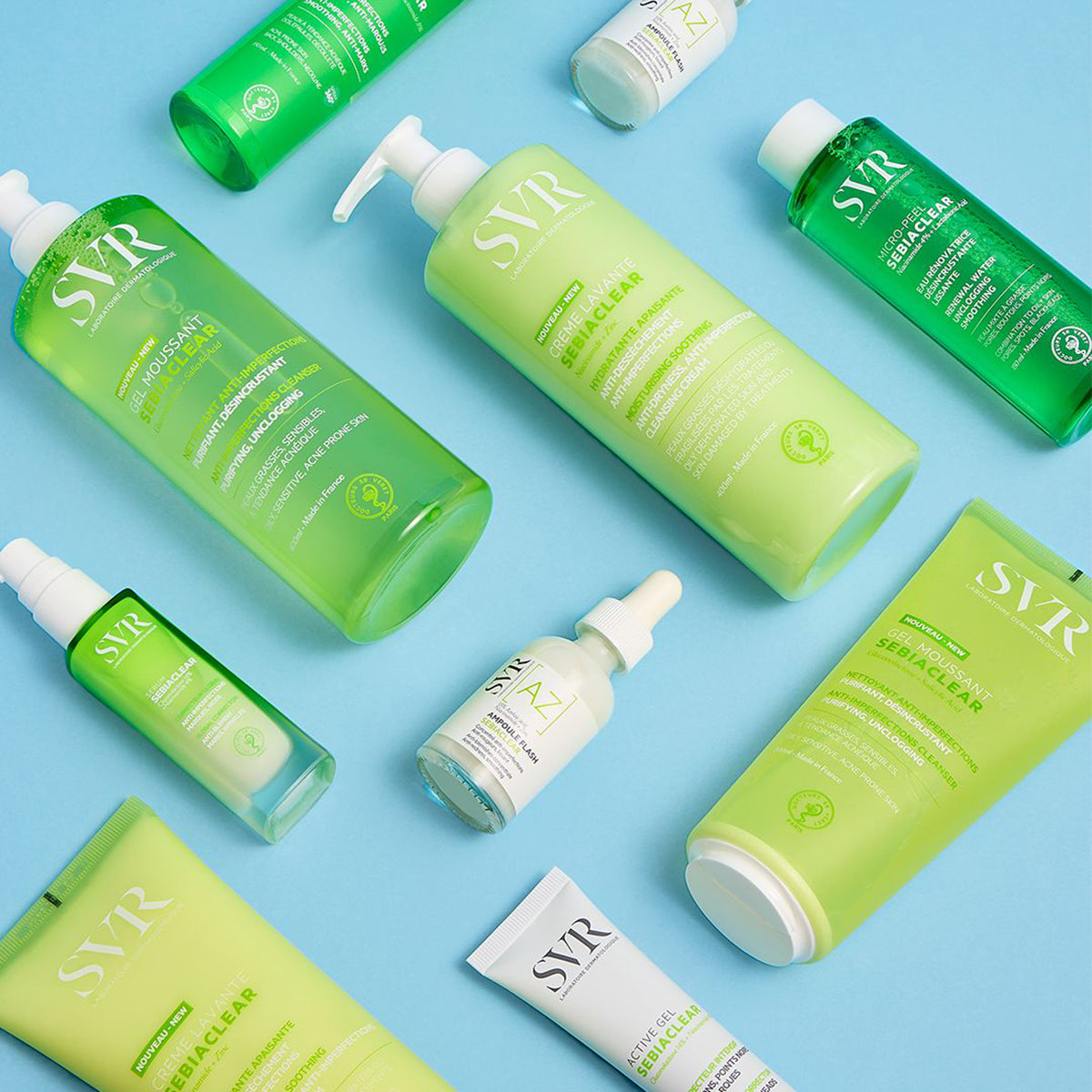 Gamme de soins SVR Sebiaclear en flacons et tubes verts et blancs sur fond bleu clair.