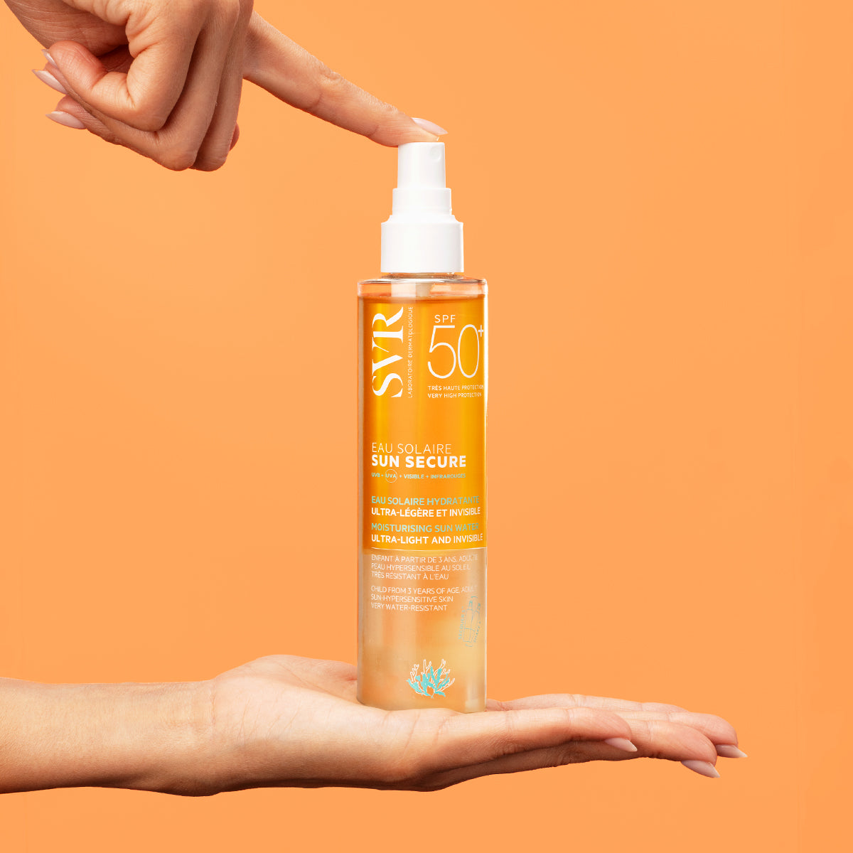 Flacon spray transparent SVR SUN SECURE Eau Solaire SPF50+ tenu entre deux mains sur fond orange vif.