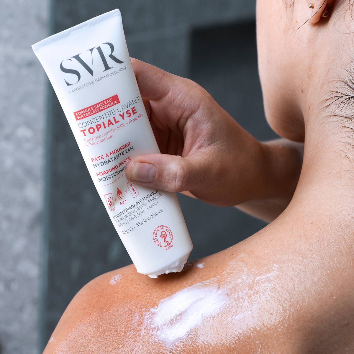 SVR TOPIALYSE Concentré Lavant white tube applying foaming moisturizing paste to a shoulder.