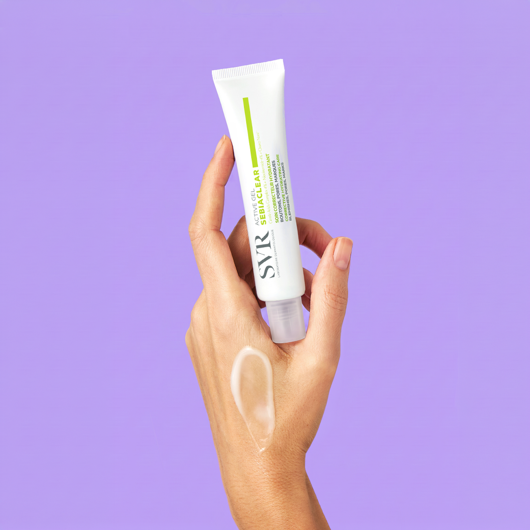 Hand holding a white SVR Sebiaclear Active Gel tube with a cream swatch on the skin against a purple background.