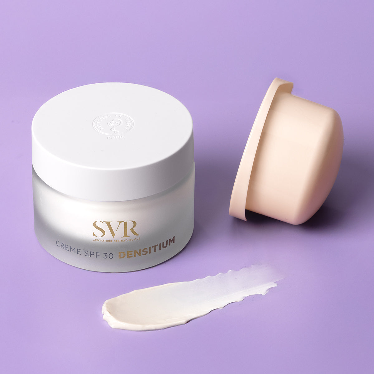 SVR Densitium SPF30 cream in a frosted glass jar with a white lid, next to a beige inner cap and a smear of white cream.
