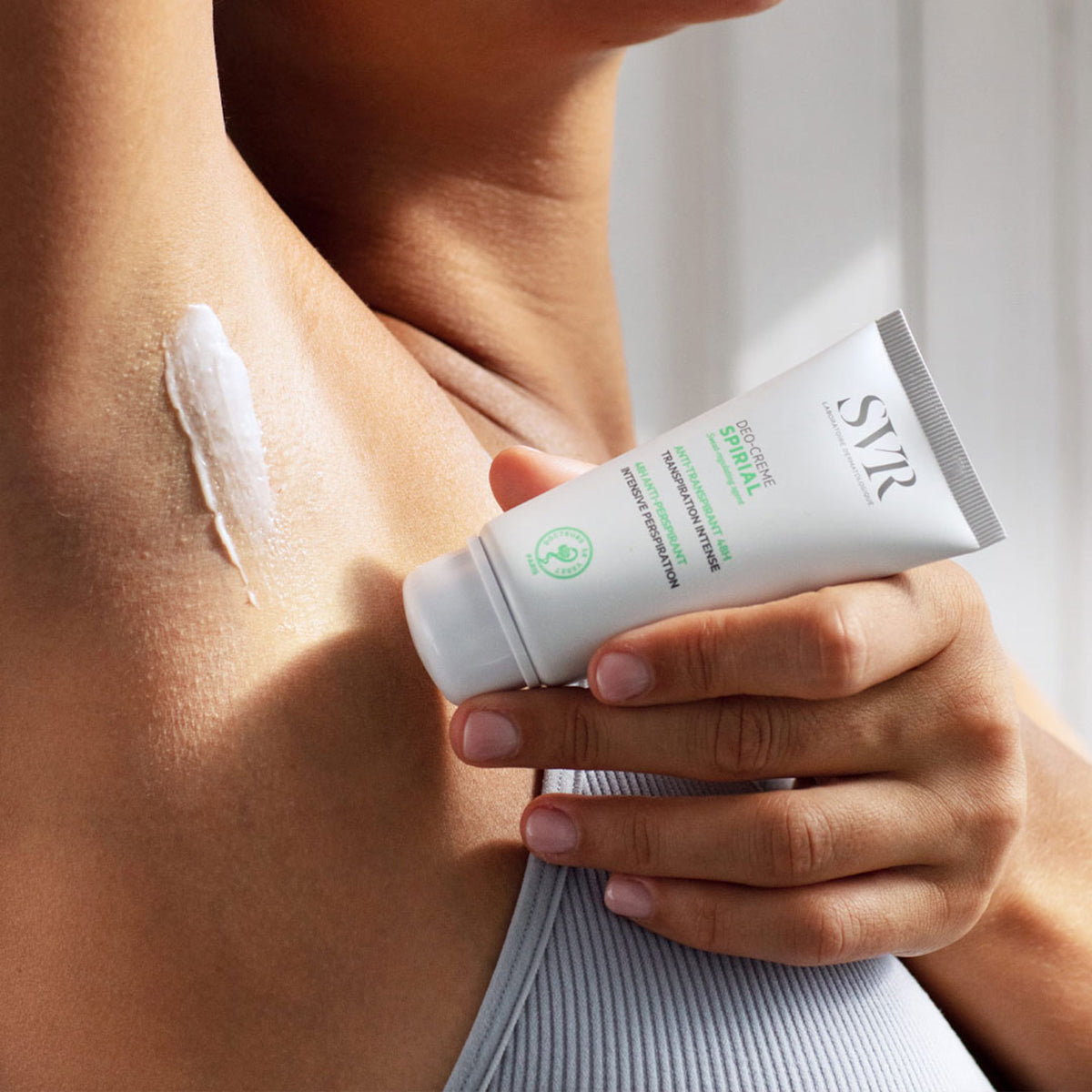 Tube de crème anti-transpirante SVR Spirial appliqué sur une aisselle pour une efficacité 48h sur peau sensible.