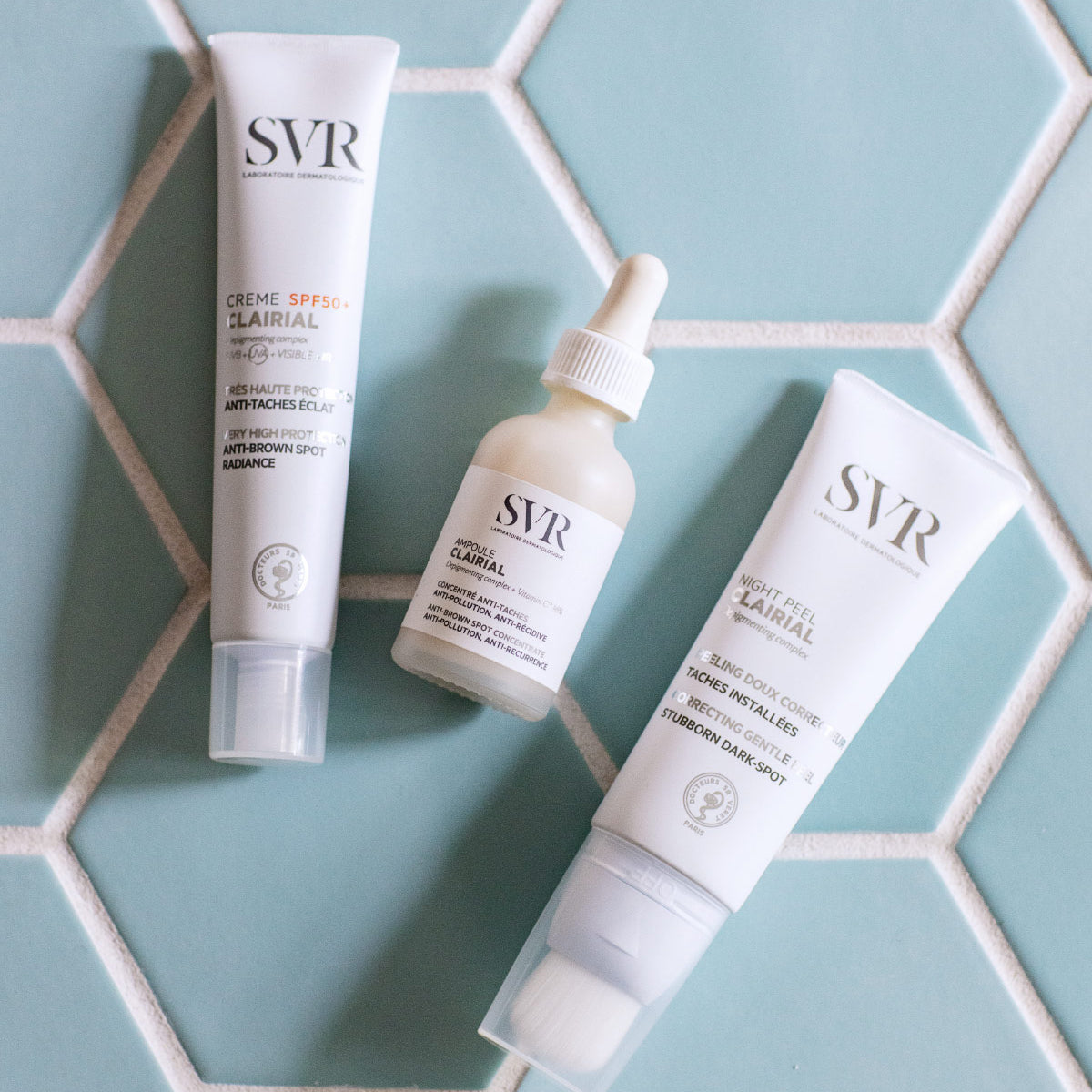 Trois produits de soin SVR Clairial sur un fond de carreaux hexagonaux bleu clair.