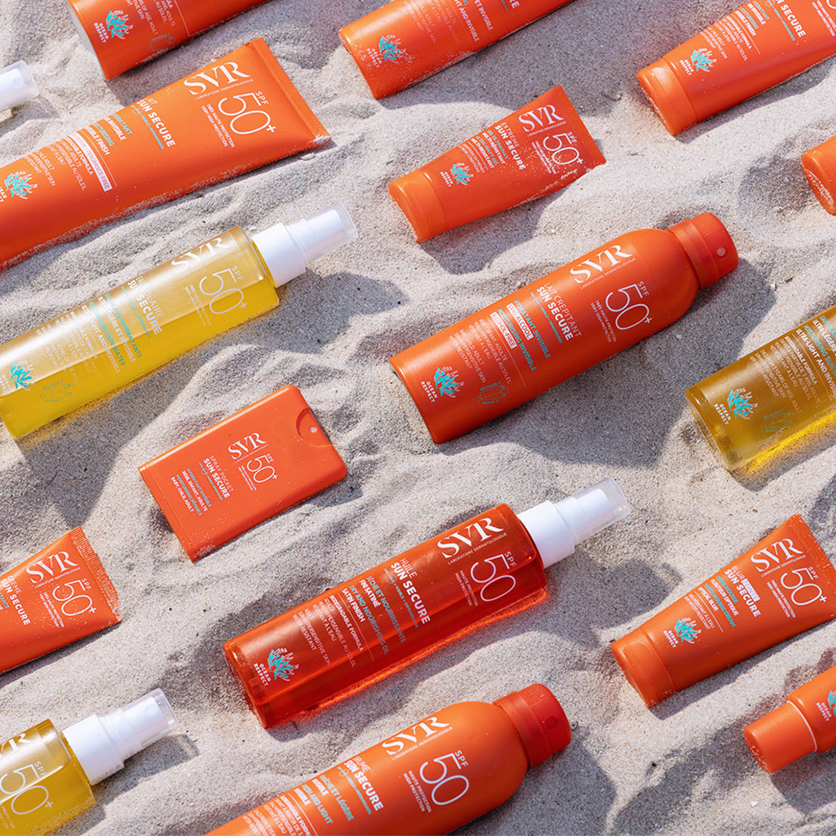 Assortiment de produits solaires SVR Sun Secure SPF50+ dans des tubes et flacons orange sur du sable de plage.