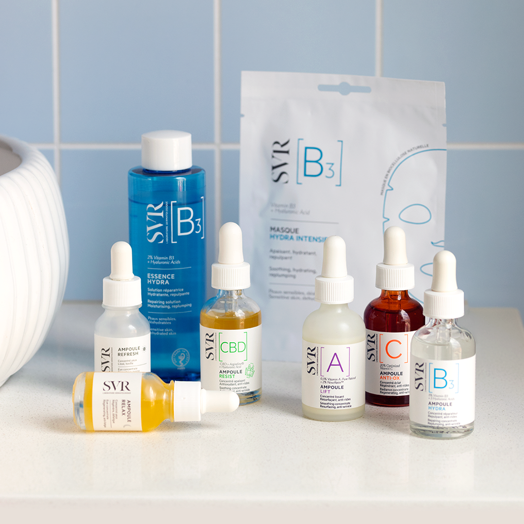 Collection de sérums SVR Ampoule et masque Hydra B3 sur un comptoir blanc devant un mur en carrelage bleu clair.