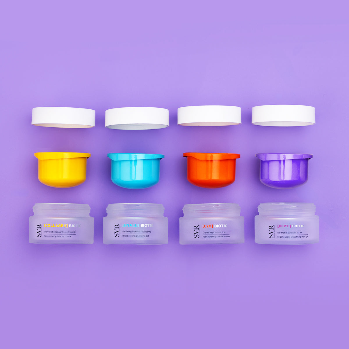 Four SVR Biotic skincare jars with colorful inner caps and white lids arranged in a row on a purple background.