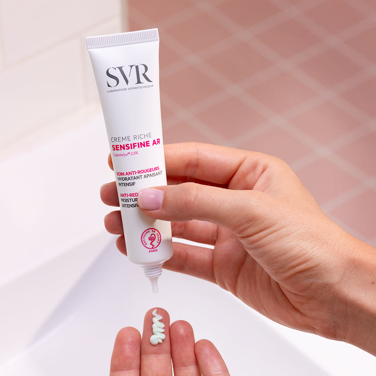Tube de crème SVR Sensifine AR Crème Riche blanc pressé à la main, délivrant une noisette de soin hydratant teinté vert.